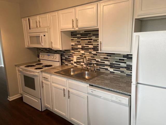 Renovated kitchen with white cabinets and tile backsplash